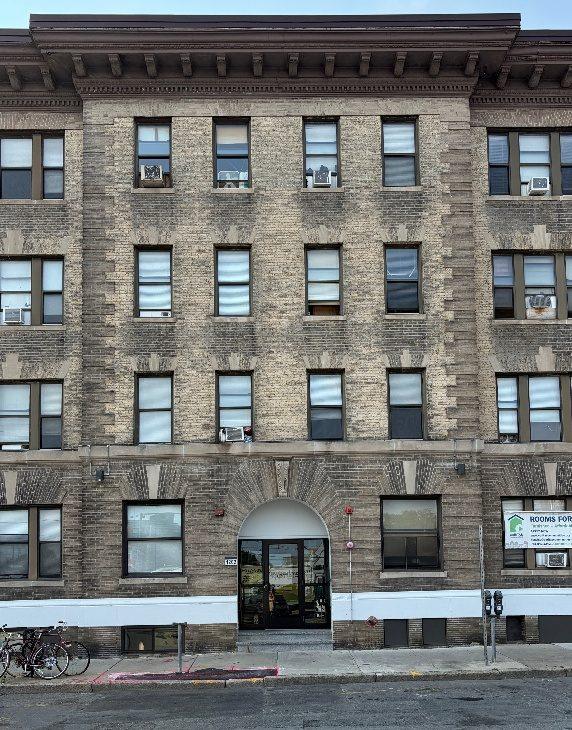 An Allston apartment building on Commonwealth Avenue with a stone base, brick middle and heavy cornice
